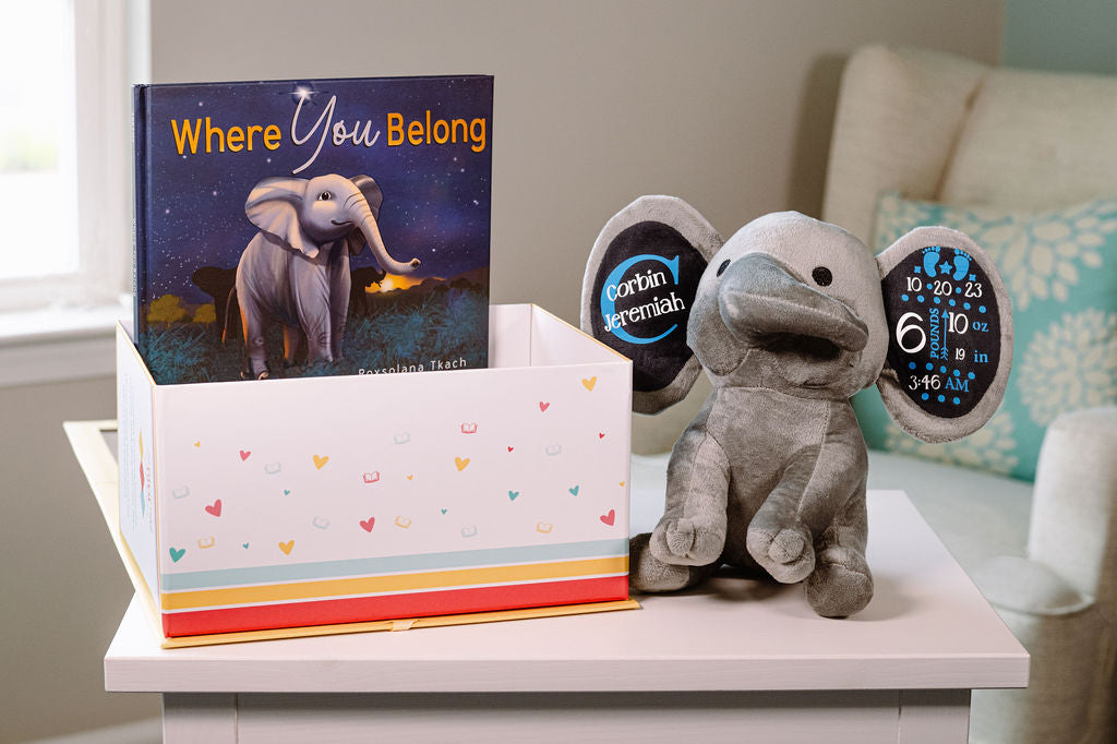 Children's book 'Where You Belong' with a plush elephant toy on a table.